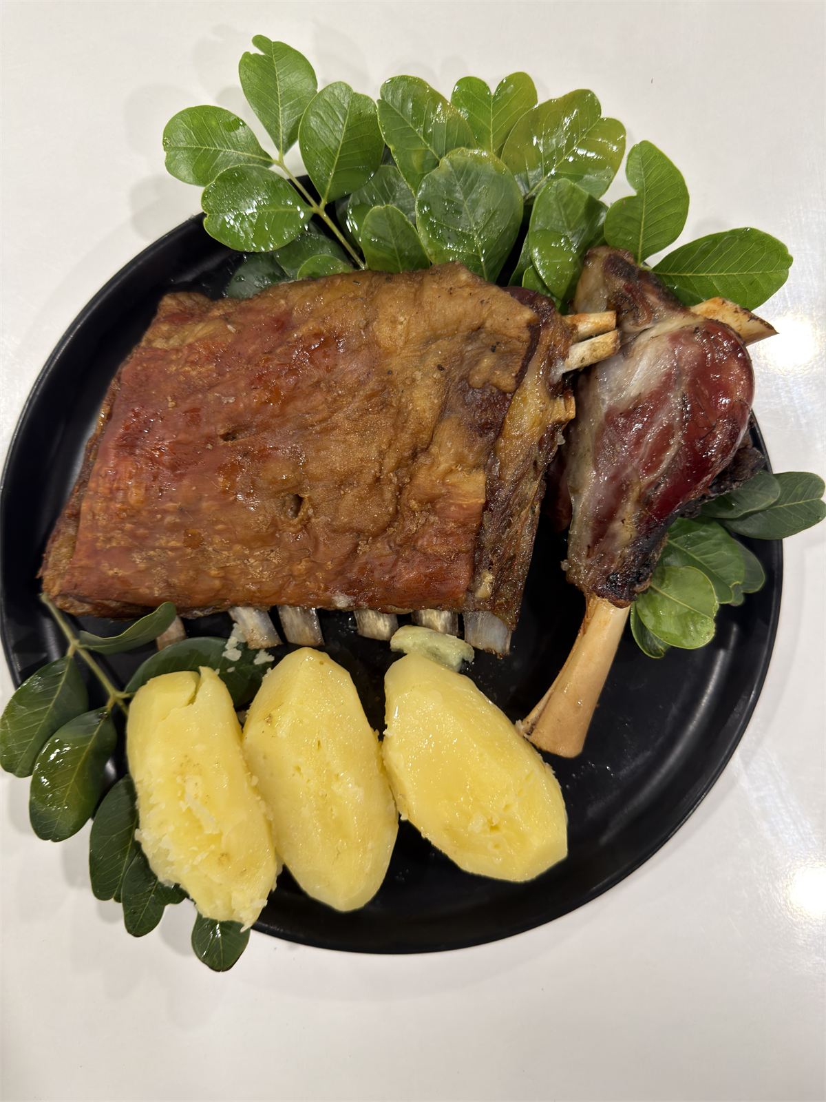Siyah tabakta Kleftiko kebabı, patates ve harnup yaprakları